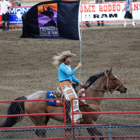 Girl riding a horse with a prorodeo hall of fame flag